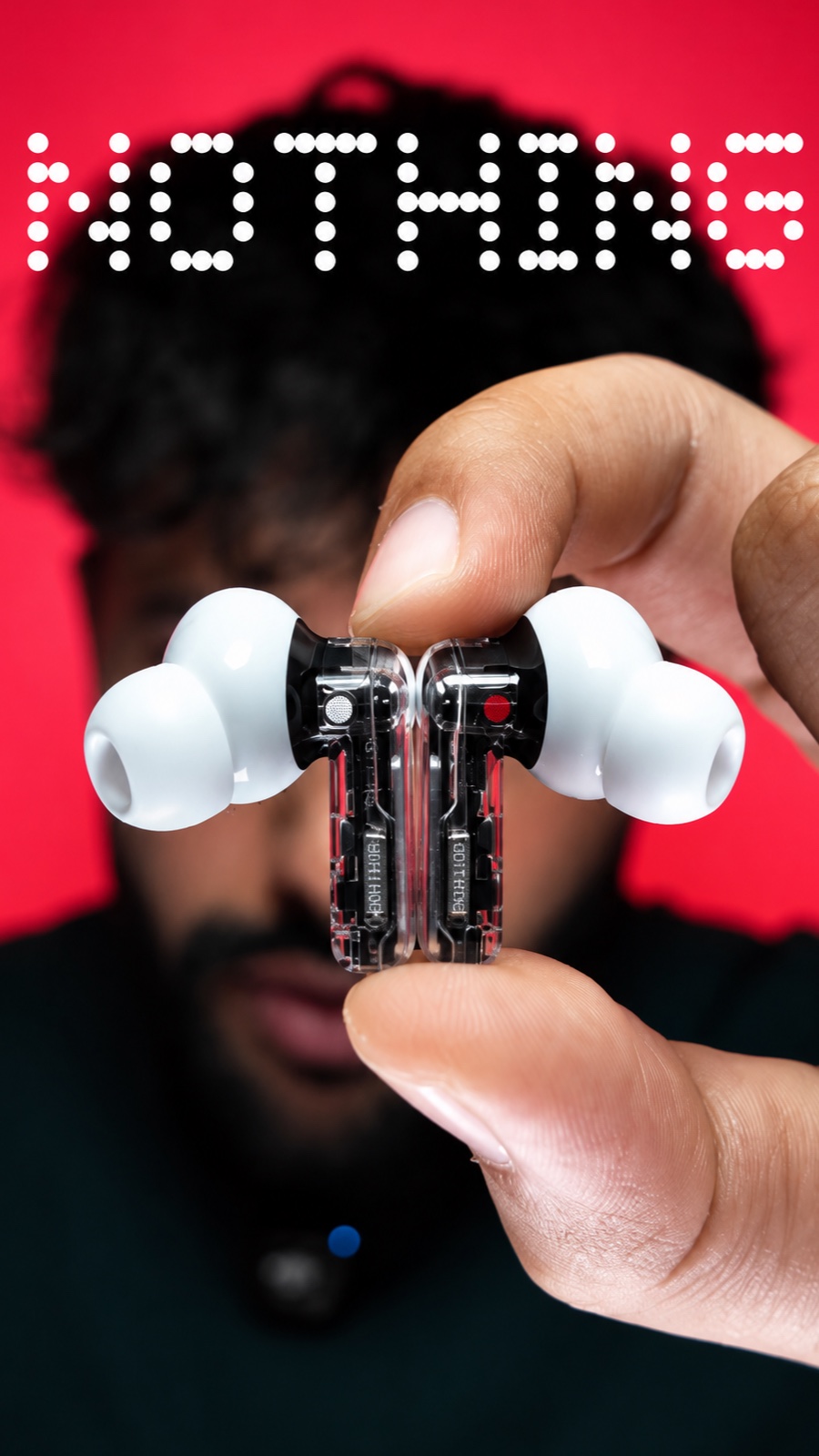 Nothing earbuds held up to the camera in front of Saqib